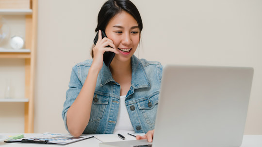 Woman talking on the phone and looking at lap top